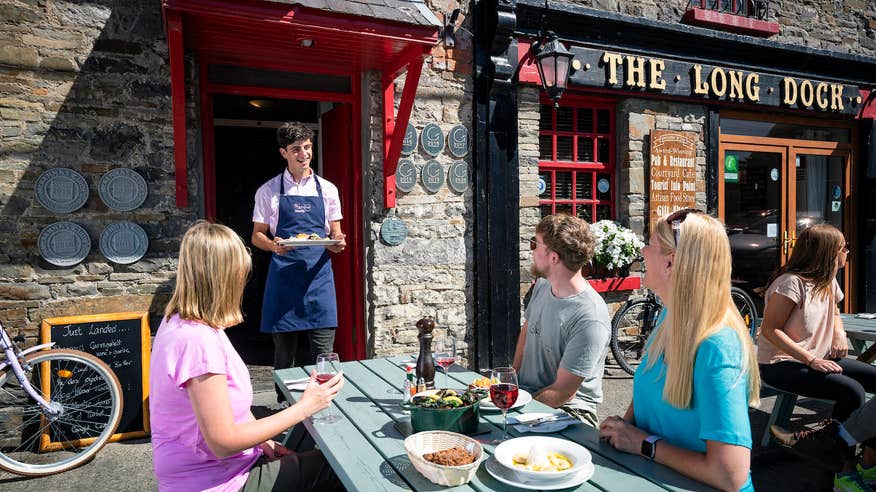 A waiter serving food to a table of people at The Long Dock restaurant in County Clare