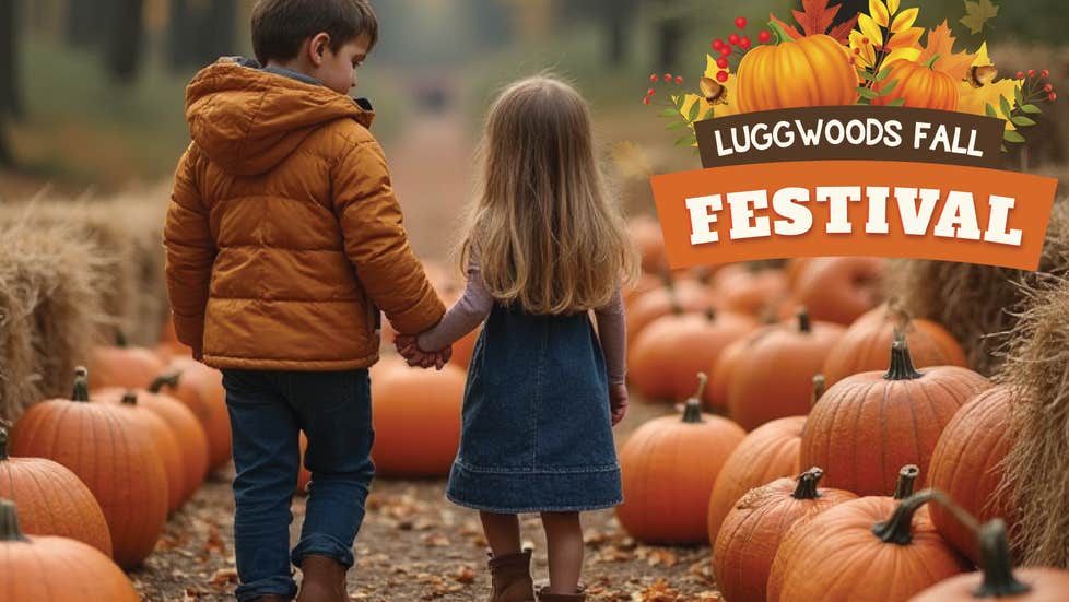 2 small children walking down a path lined with large pumpkins and bales of hay.
