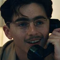 Close up view of man in glasses, smiling talking on an old style telephone.