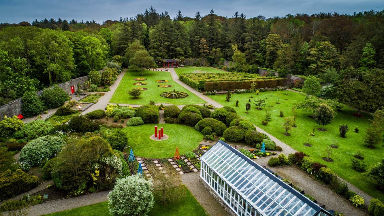 An aerial view across a walled garden with a glasshouse in the foreground