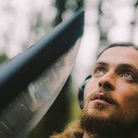 Cork ornithologist Seán Ronayne, a man outdoors wearing overear headphones looking upwards.