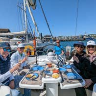 Four people on a yacht sitting around a small table with food platters