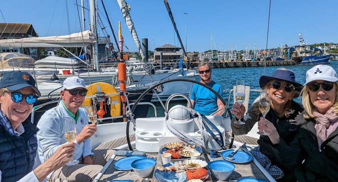Four people on a yacht sitting around a small table with food platters