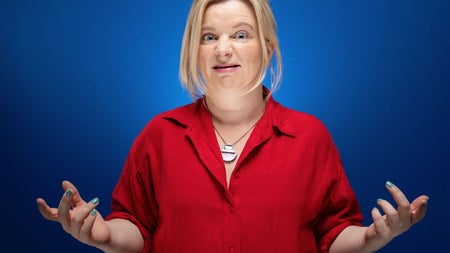 Comedian Sharon Mannion wearing a red shirt with a blue background