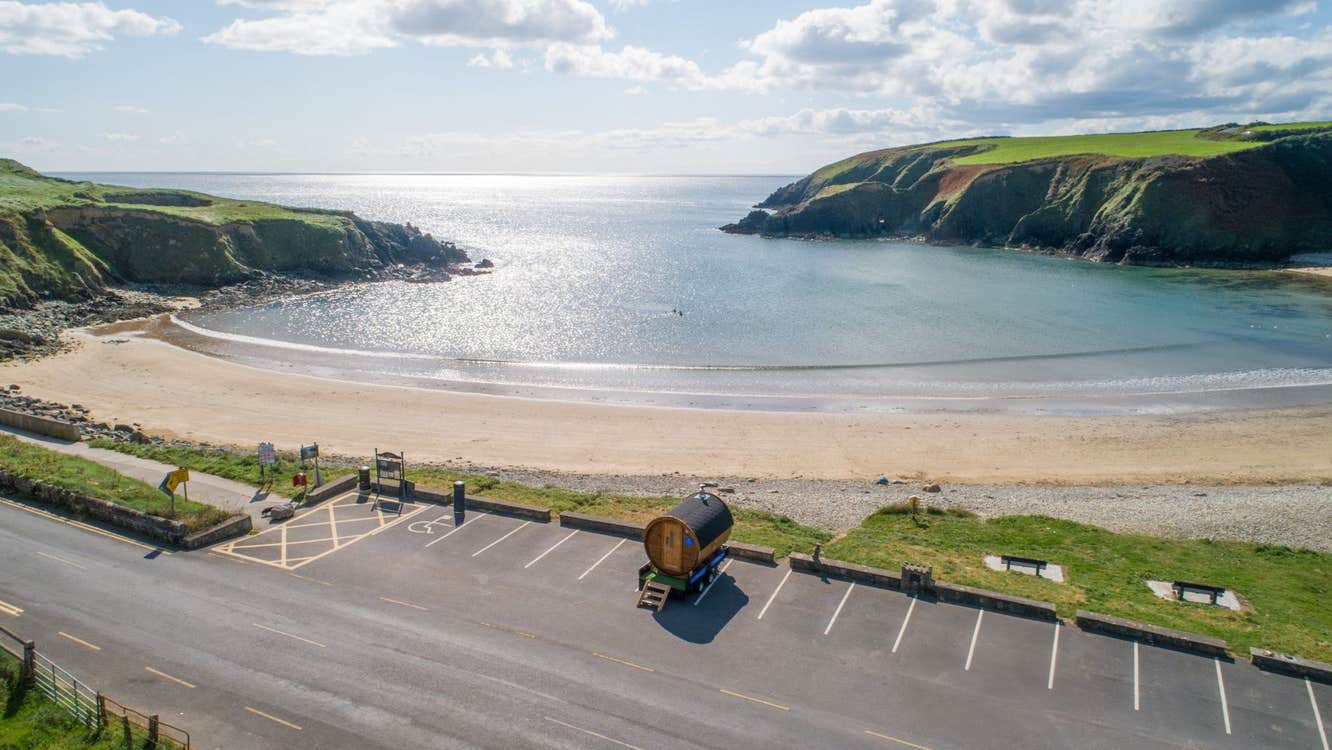 An aerial view of a mobile wooden sauna overlooking a beach