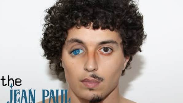 Clayton Pettet, known as Babymorocco, a man's head with curly dark hair and mismatched eyes, one brown the other blue and drooping down at the outer edge.