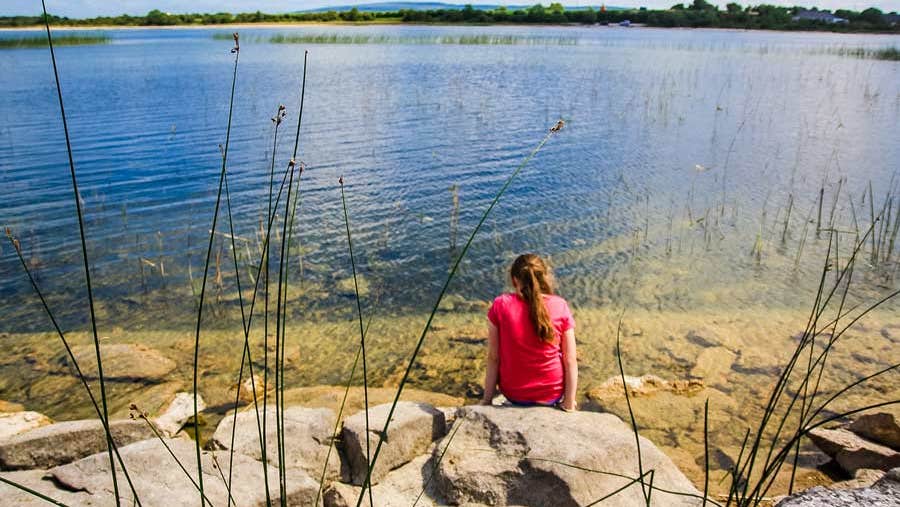 Girl sitting on the edge of a lake