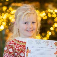 A smiling young girl holding up a piece of paper
