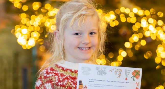 A smiling young girl holding up a piece of paper