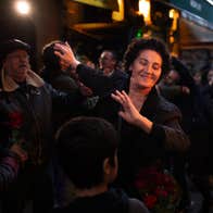 In a crowd at night a woman is dancing, smiling with her eyes closed.