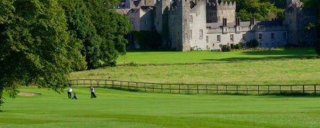 Golfers playing golf with a castle in the background