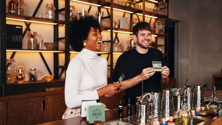Two people standing behind a bar laughing