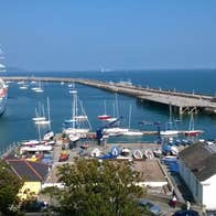 A view of a harbour with small boats and one large ship with tall masts