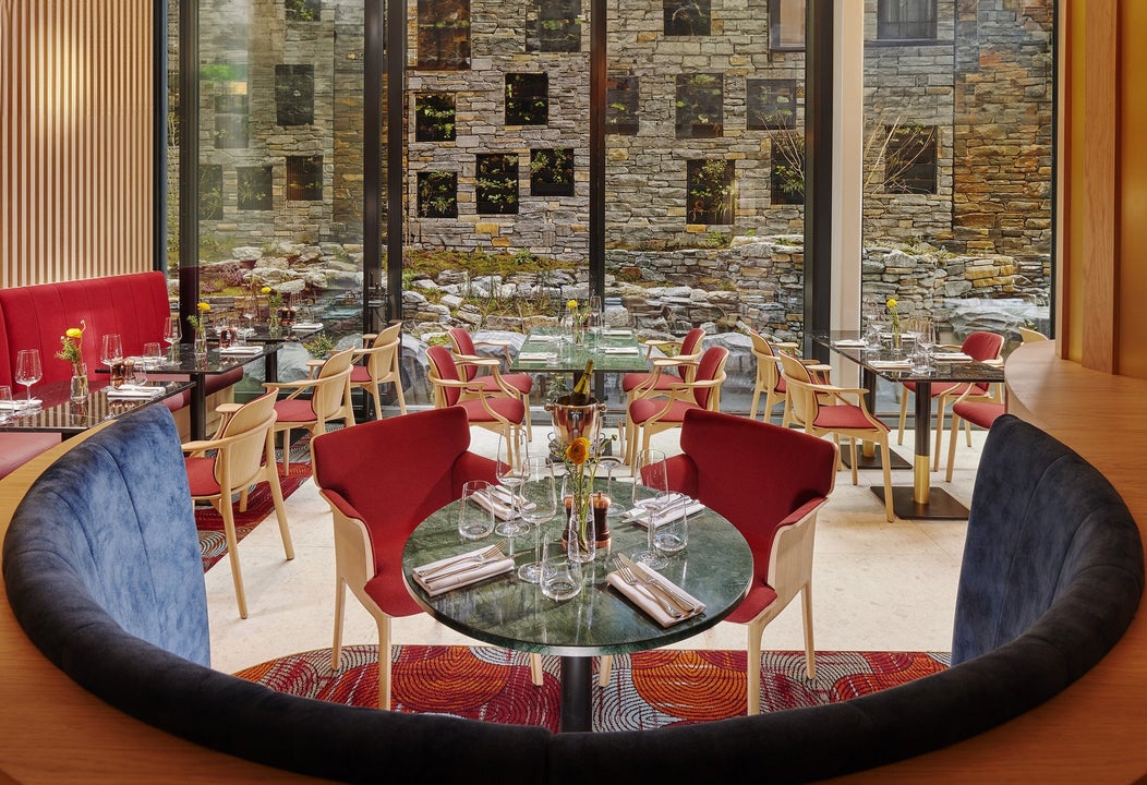 Cushioned booth with a round table set for service surrounded by more tables in a restaurant