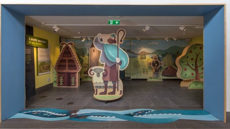 Exhibition with a cut out of a sheep and a shepherd holding a staff