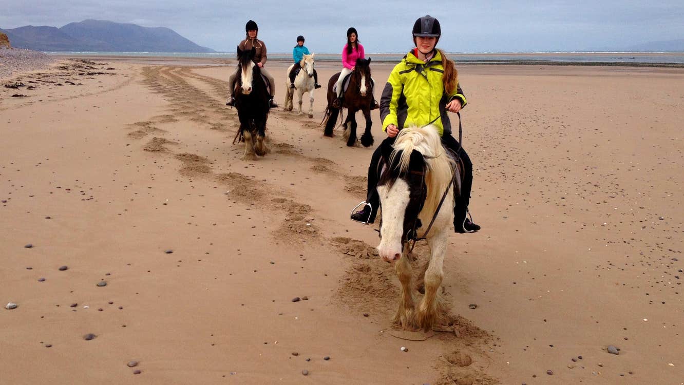 Four girls pony trekking along a sandy beach