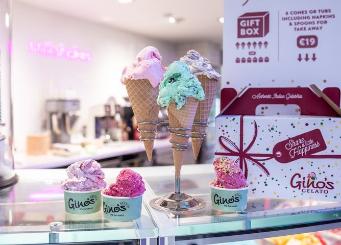 Colourful ice cream in cones and pots sitting on a shop counter