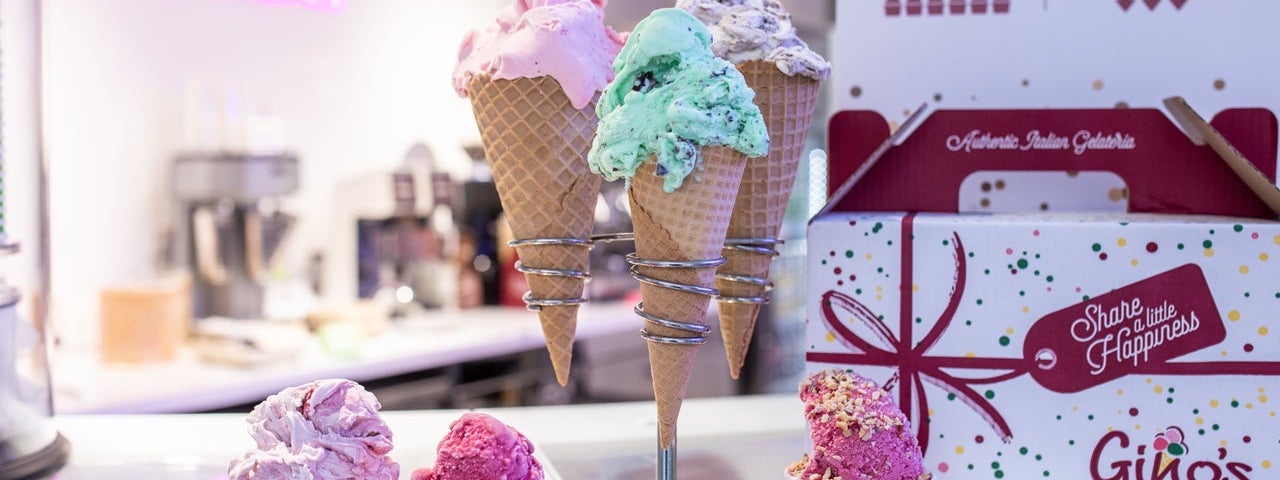 Colourful ice cream in cones and pots sitting on a shop counter