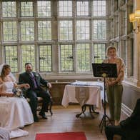 Bride and groom sitting as a celebrant speaks to seated guests