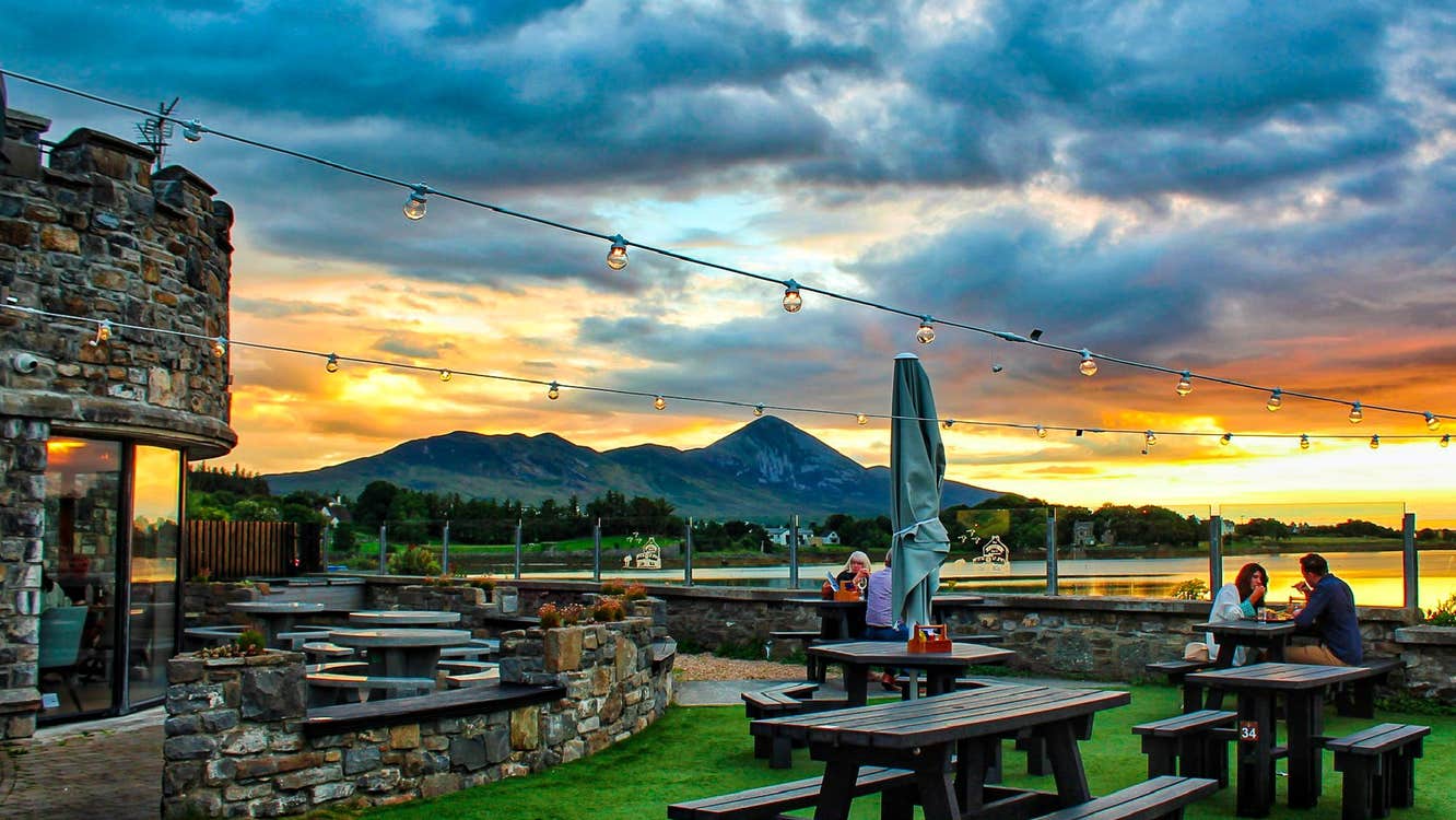Sunset behind the Tower Garden with customers seated at wooden picnic style benches