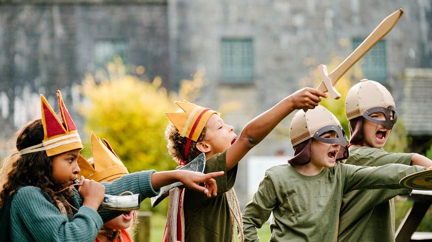 Young kids in costume playing games with swords and helmets