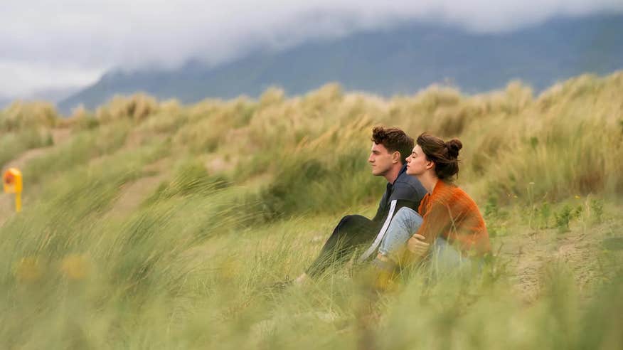 A scene from the series 'Normal People', featuring a couple, male and female sitting amongst the marram grass on a beach in county Sligo.