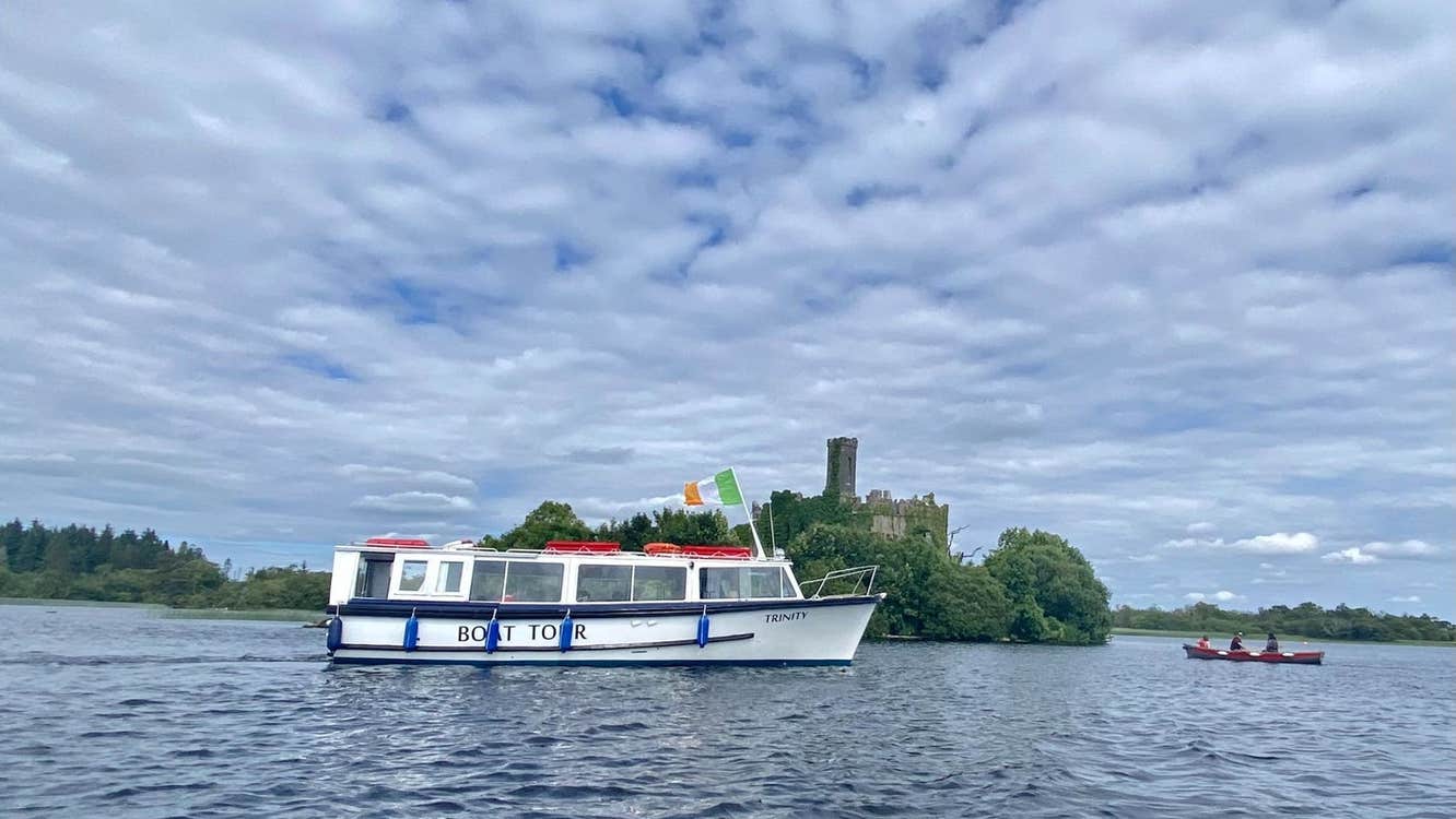 A tour boat cruising by an island on a lake with a castle ruin