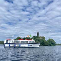 A tour boat cruising by an island on a lake with a castle ruin