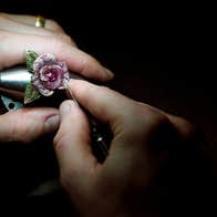 A flower shaped luxury piece of jewellery being worked on by hand