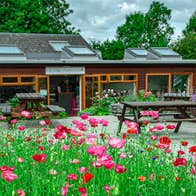 The gift shop and cafe at Brigits Garden with blossoming red flowers in foreground