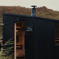 Two people using Skellig Sauna a lady entering the sauna and a gentleman relaxing inside