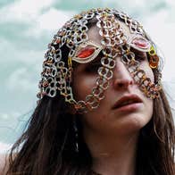 A person with long dark hair wearing a head and partial face covering made from interlinked chains.