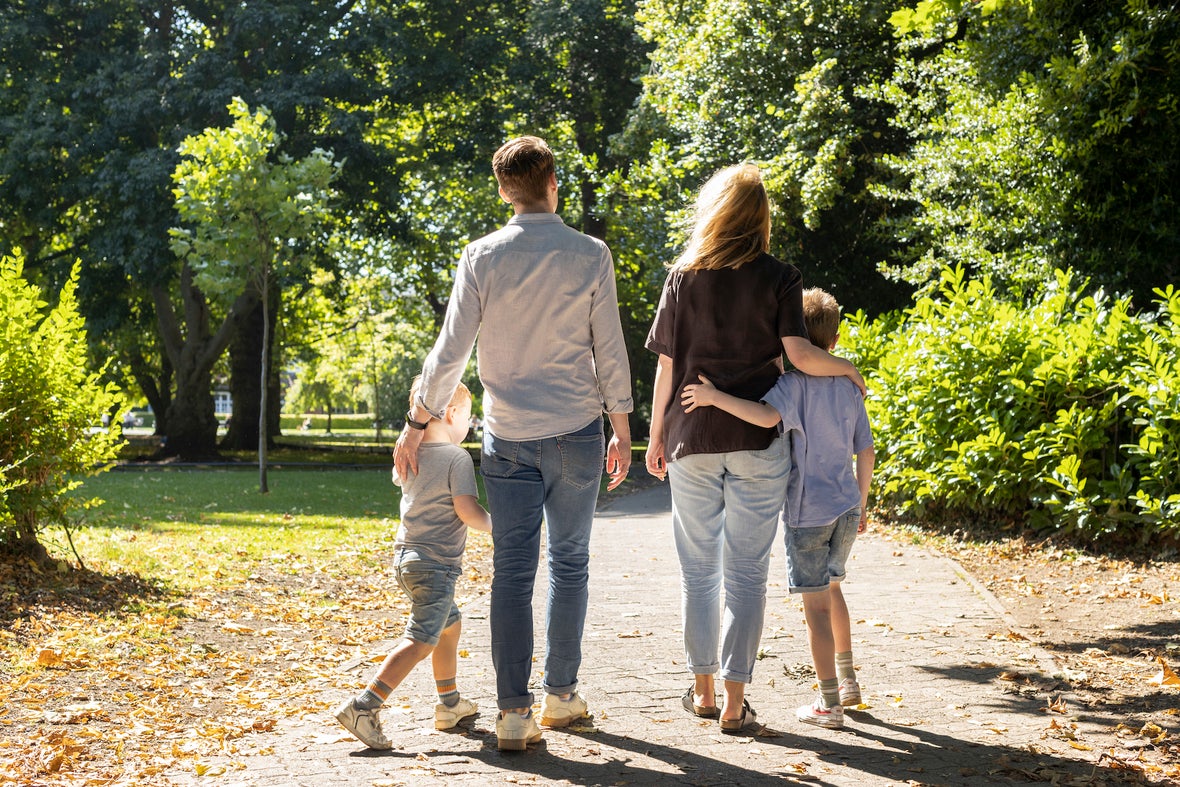 A family of four walking through St Stephen's Green in Dublin city on a sunny day.