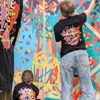 Rear view of youngsters in matching T-shirts working on art on a wall