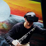 Music Current 2026 _ Ressi Benes, a man wearing a VR headset and holding a clarinet is reaching out with his other hand.