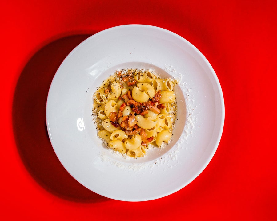 A dish of pasta on a white bowl on a red table cloth at TONI Italian restaurant 