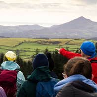 A hiking guide points out a distant feature to a group of hikers