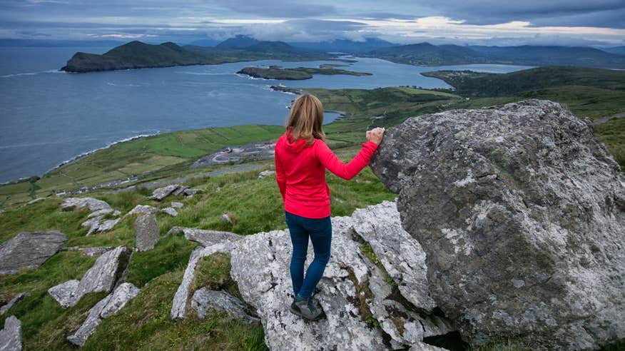 A woman in a red jacket hiking by the sea on Valentia Island, Co Kerry