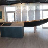 A display featuring a currach boat with images of fishermen in the background