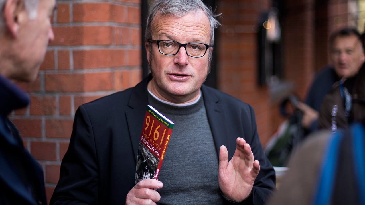 The tour guide holding a book about 1916 while speaking to the group