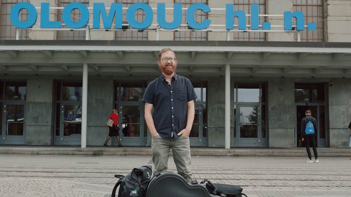 A master storyteller, Niall Connolly, a man standing in front of a building with guitar case and bags