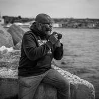 A man with a camera next to a body of water.