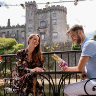 A couple sitting at a table with Kilkenny Castle in the background in County Kilkenny.