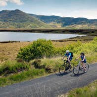 Two people cycling on The Great Western Greenway beside the sea in Mayo