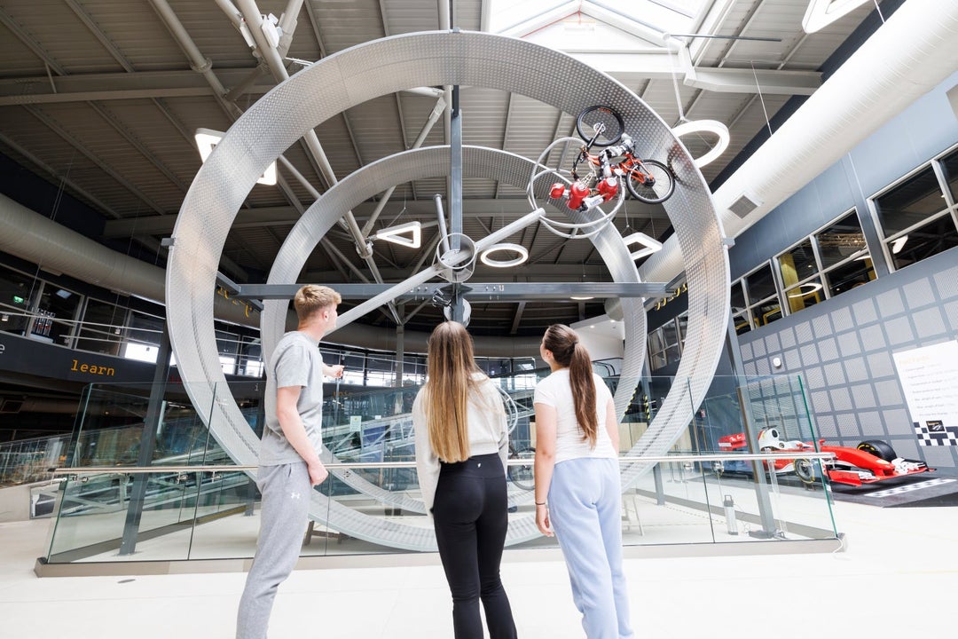 Children looking at metal rings with a bicycle and robot rider cycling along the circuit