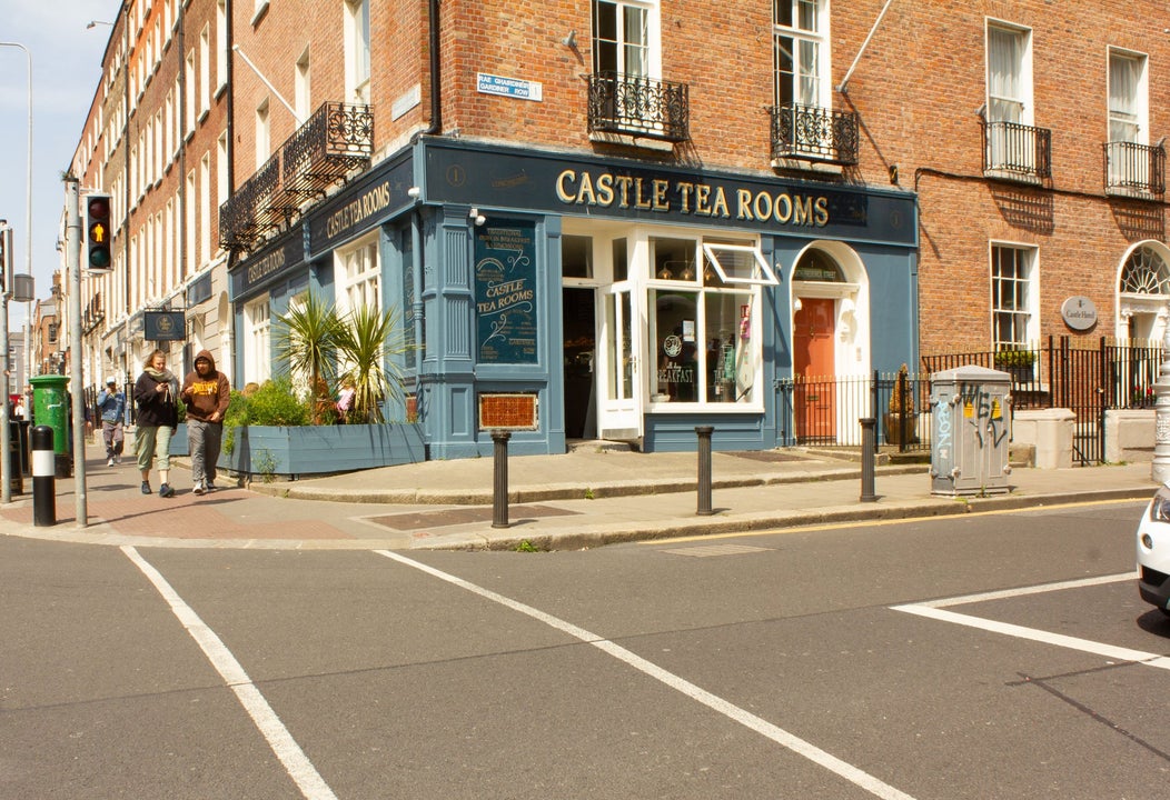 Street view of a blue coffee shop on a corner with people walking past