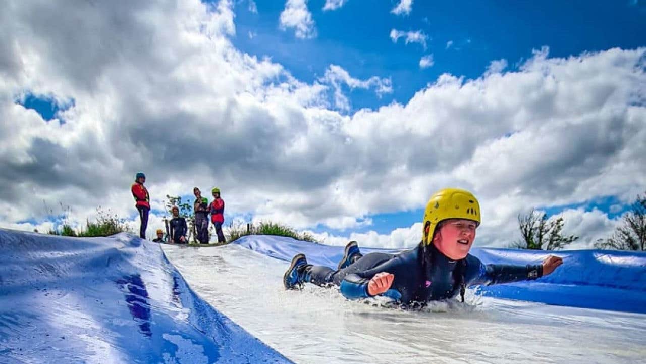 A child slides down the mud splash slide at Shannon River Adventure