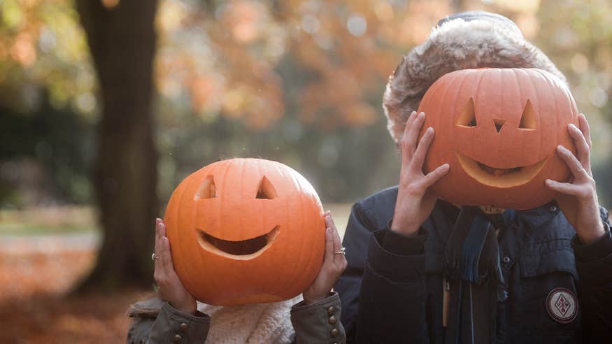 Two kids playing with Jack-o-lanterns at Halloween.