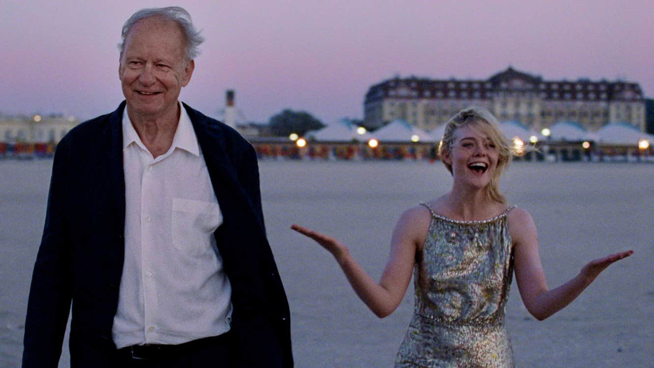 A joyous old man and young woman are on a beach.