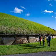 People walking beside the Knowth Neolithic tomb in Co Meath